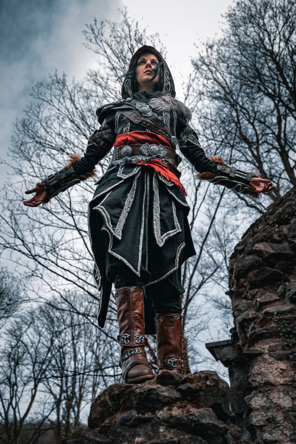 Ein Bild von einem Ezio Auditore Cosplay. Ezio steht auf einer Mauer, als würde er herunterspringen wollen.